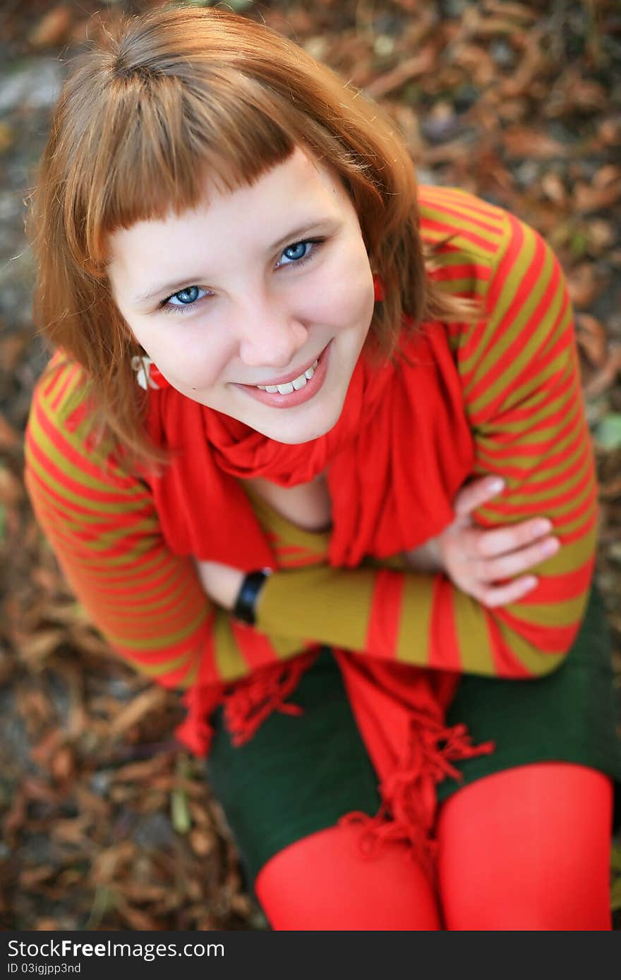 Portrait of a girl in a bright colored striped sweater lying on the grass. Portrait of a girl in a bright colored striped sweater lying on the grass