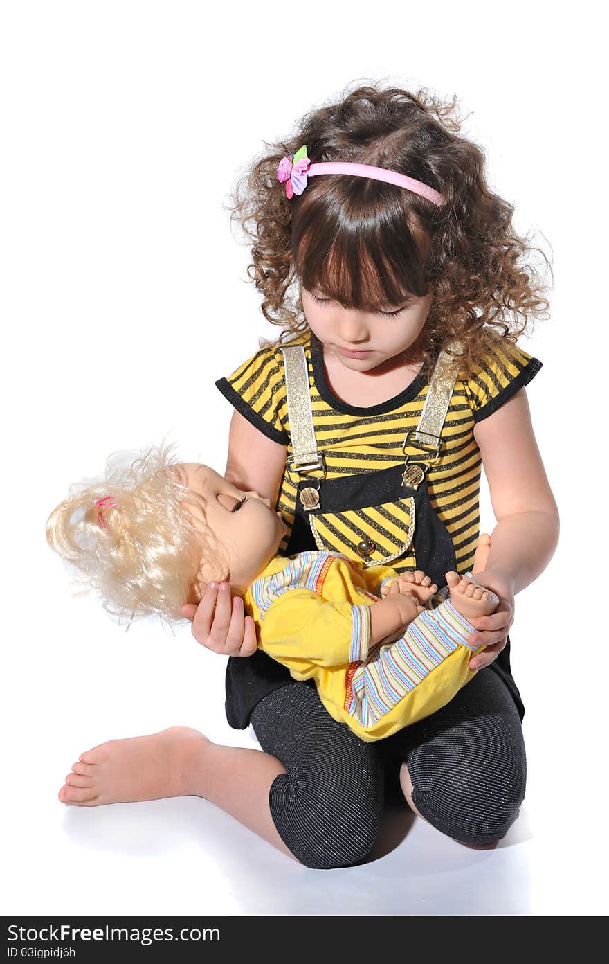 Portrait of sweet little girl playing with the doll in studio on white background. Portrait of sweet little girl playing with the doll in studio on white background