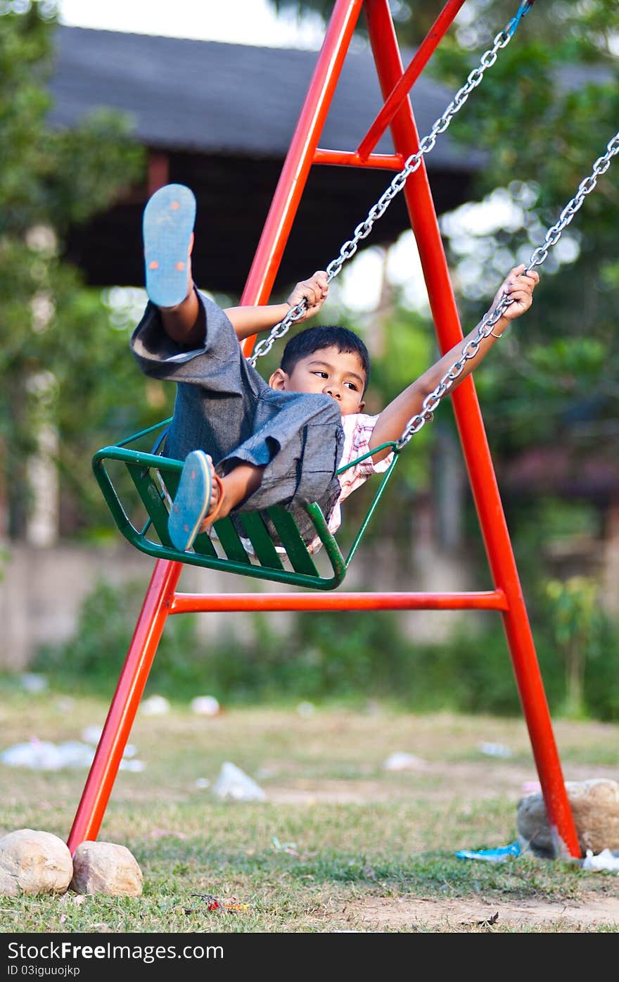 Asian boy playing swing at playground