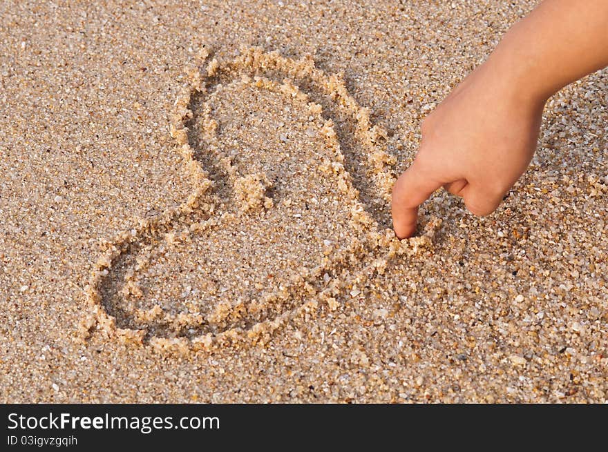 Writing heart on sand in warm light. Writing heart on sand in warm light