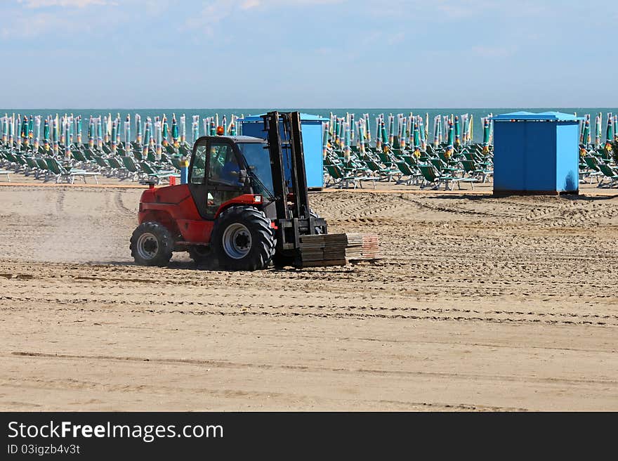 A fork-truck is bringing promenade tiles to the beach. A fork-truck is bringing promenade tiles to the beach