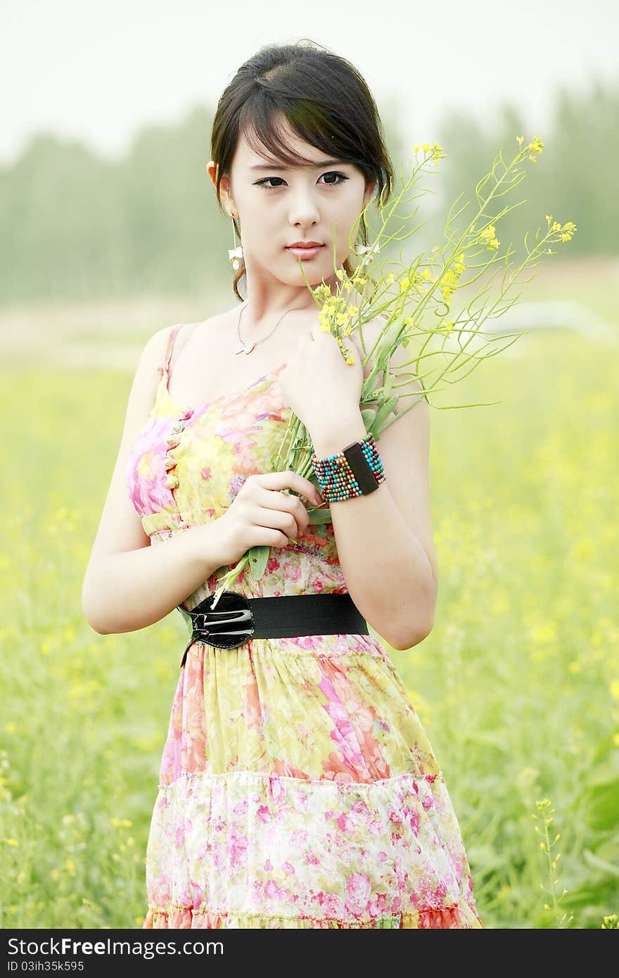 Asian summer girl holding a bunch of flowers in field. Asian summer girl holding a bunch of flowers in field.