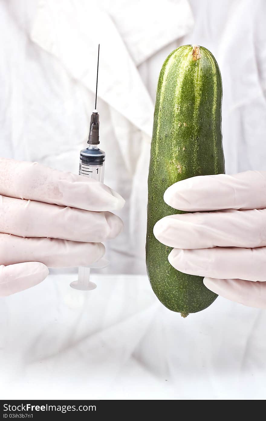 Cucumber and syringe in hands of the inspector on quarantine in a white dressing gown