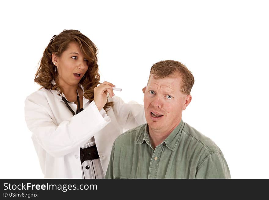 A women doctor checking her patients ear by using a light. They both have shocked expressions on their faces. A women doctor checking her patients ear by using a light. They both have shocked expressions on their faces.