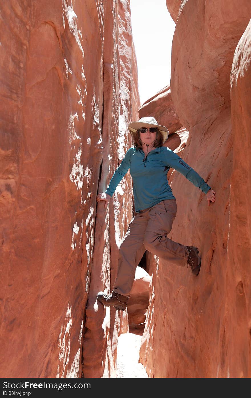 Woman hiker poses at a beautiful sandstone arch in Arches National Park. Woman hiker poses at a beautiful sandstone arch in Arches National Park