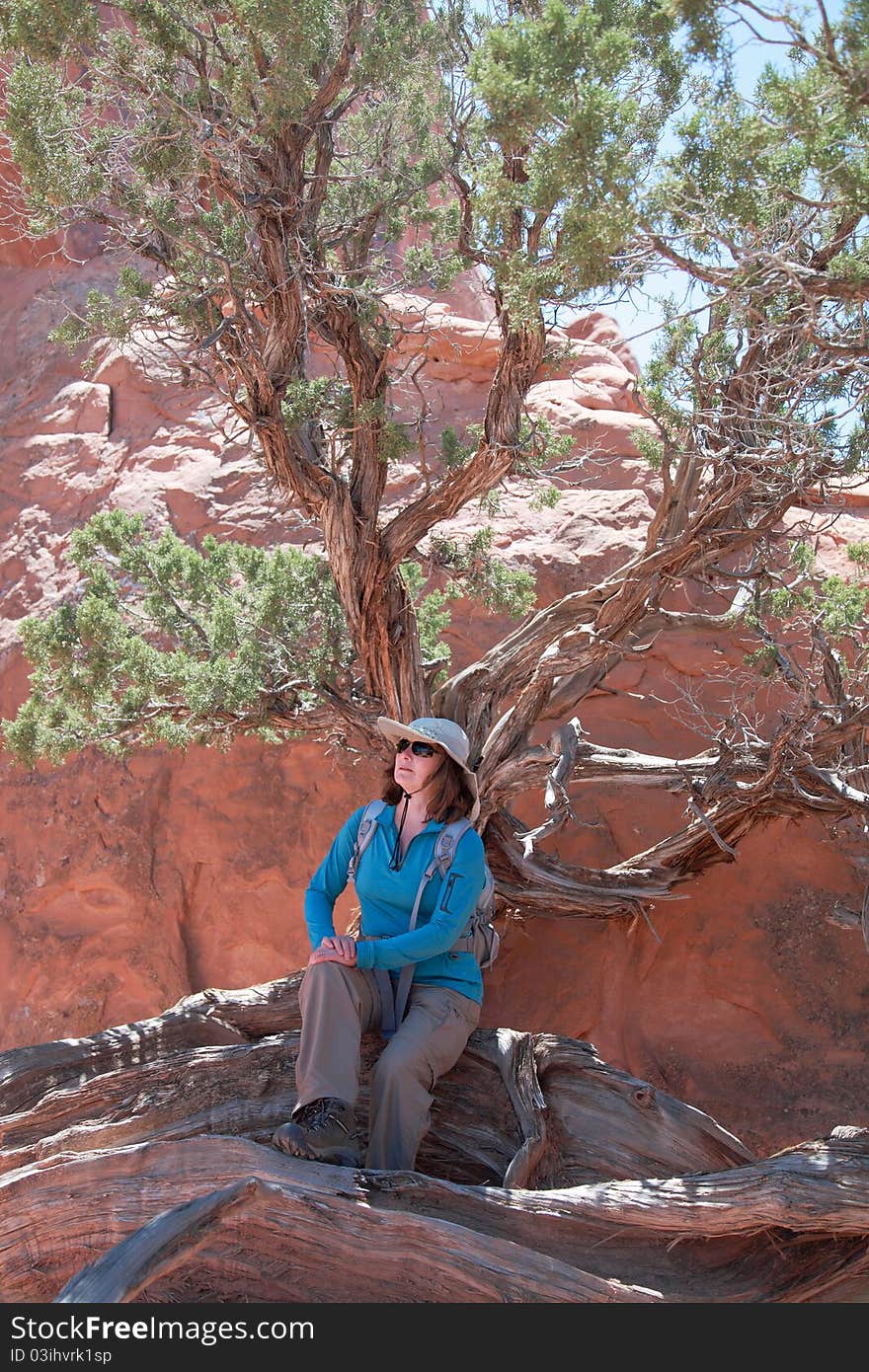 Woman hiker poses at a beautiful sandstone arch in Arches National Park. Woman hiker poses at a beautiful sandstone arch in Arches National Park