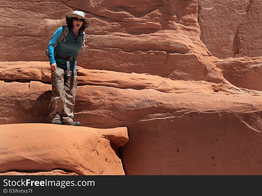 Woman hiker considers the fall potential in Arches National Park. Woman hiker considers the fall potential in Arches National Park