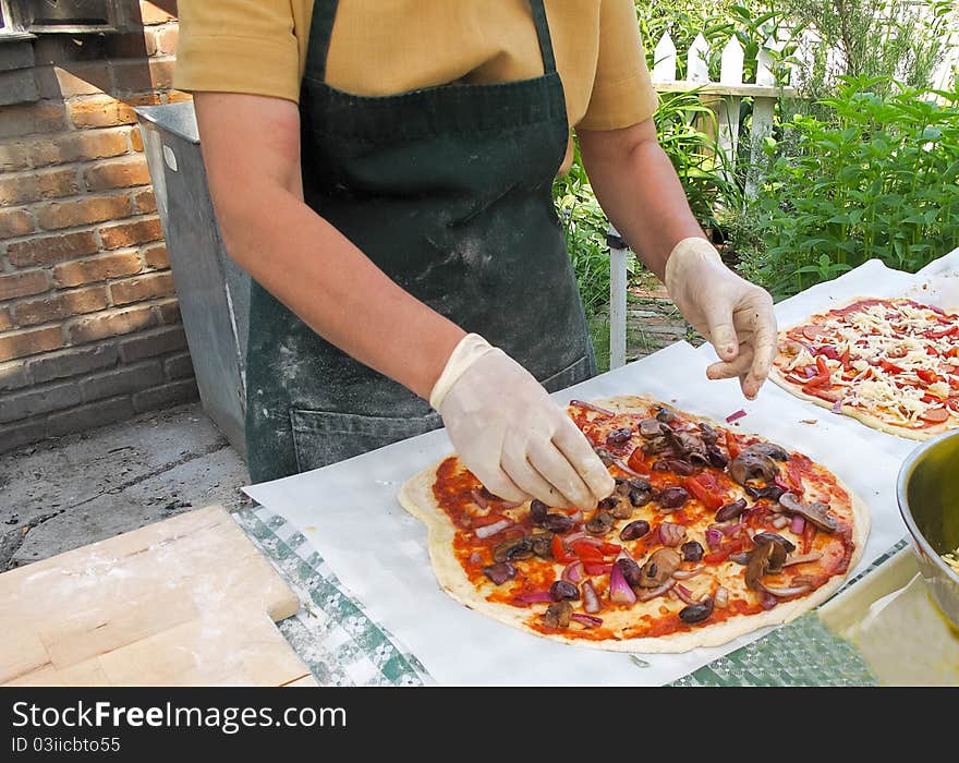 Adding toppings to organic pizza at outdoor market. Adding toppings to organic pizza at outdoor market