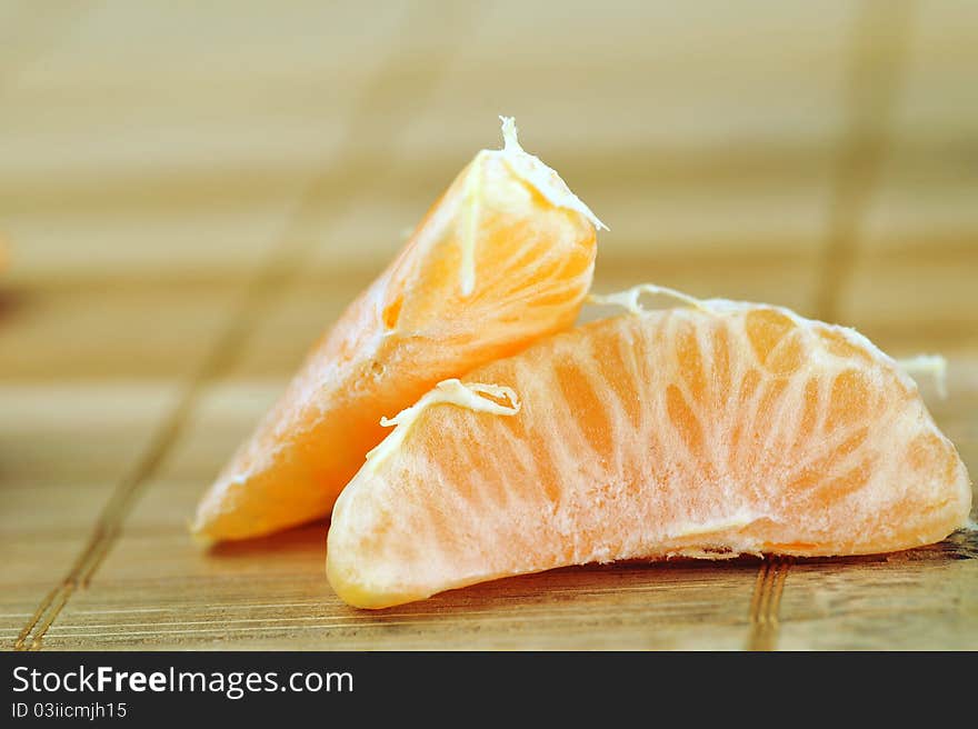 Segments of delicious juicy tangerine on bamboo napkin close up. Segments of delicious juicy tangerine on bamboo napkin close up