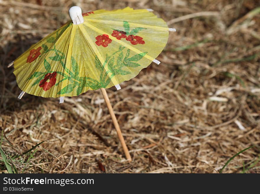 It is a small umbrella fixed in a dry grass. It is a small umbrella fixed in a dry grass.