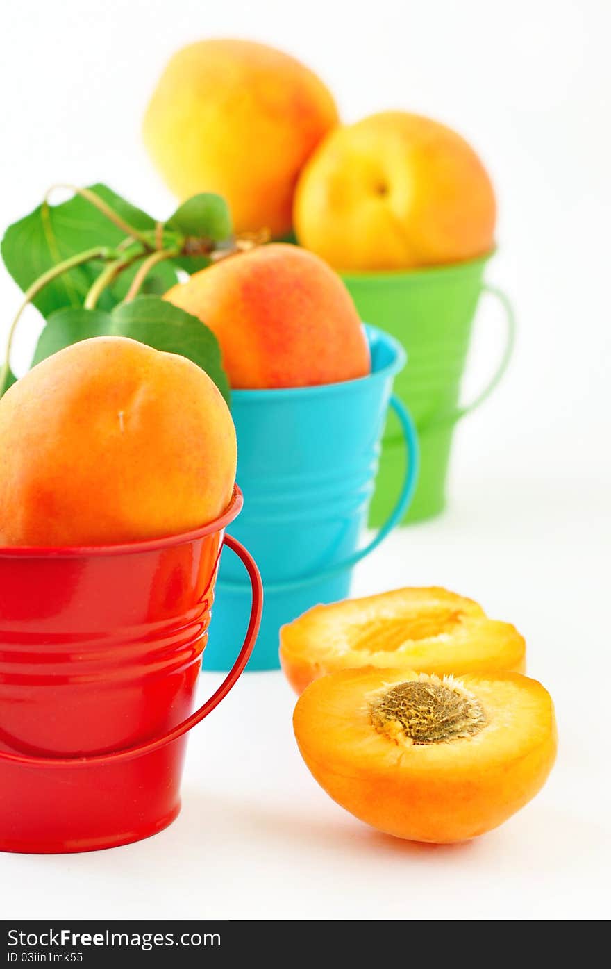 Apricots in buckets on a white background