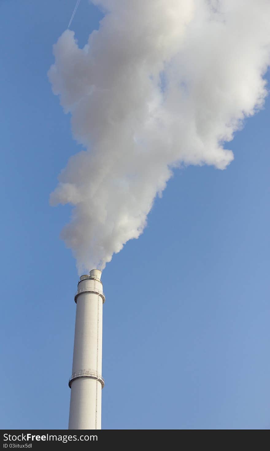 View of smoking smokestack against blue sky