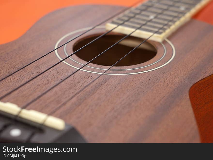 Ukulele guitar on orange background, Close-up shot.