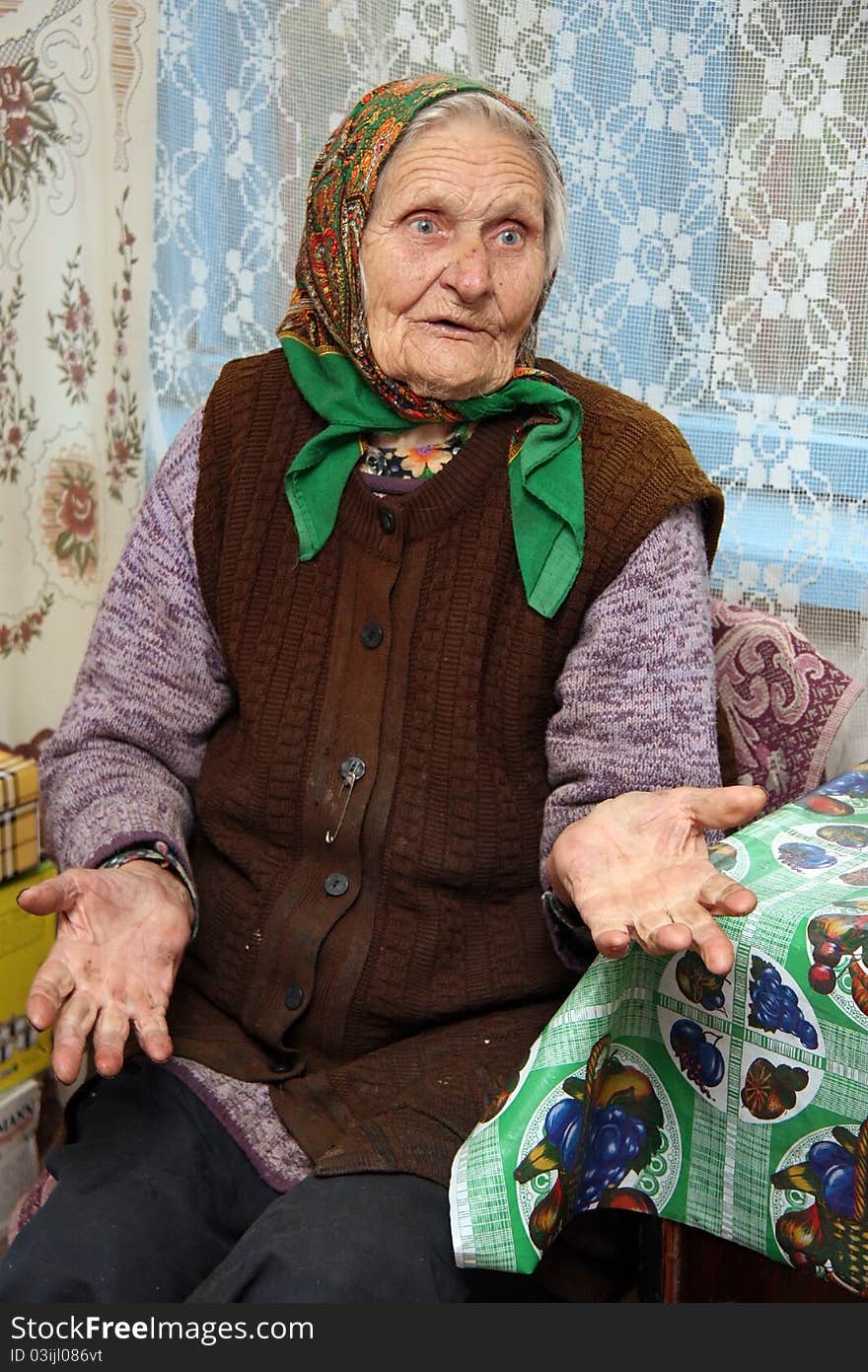 Merry grandmother sitting at the table on a background window