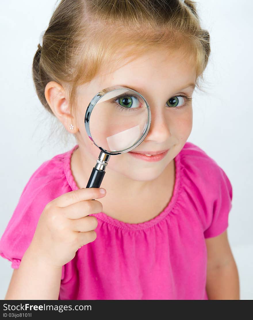 Little girl looking through a magnifying glass