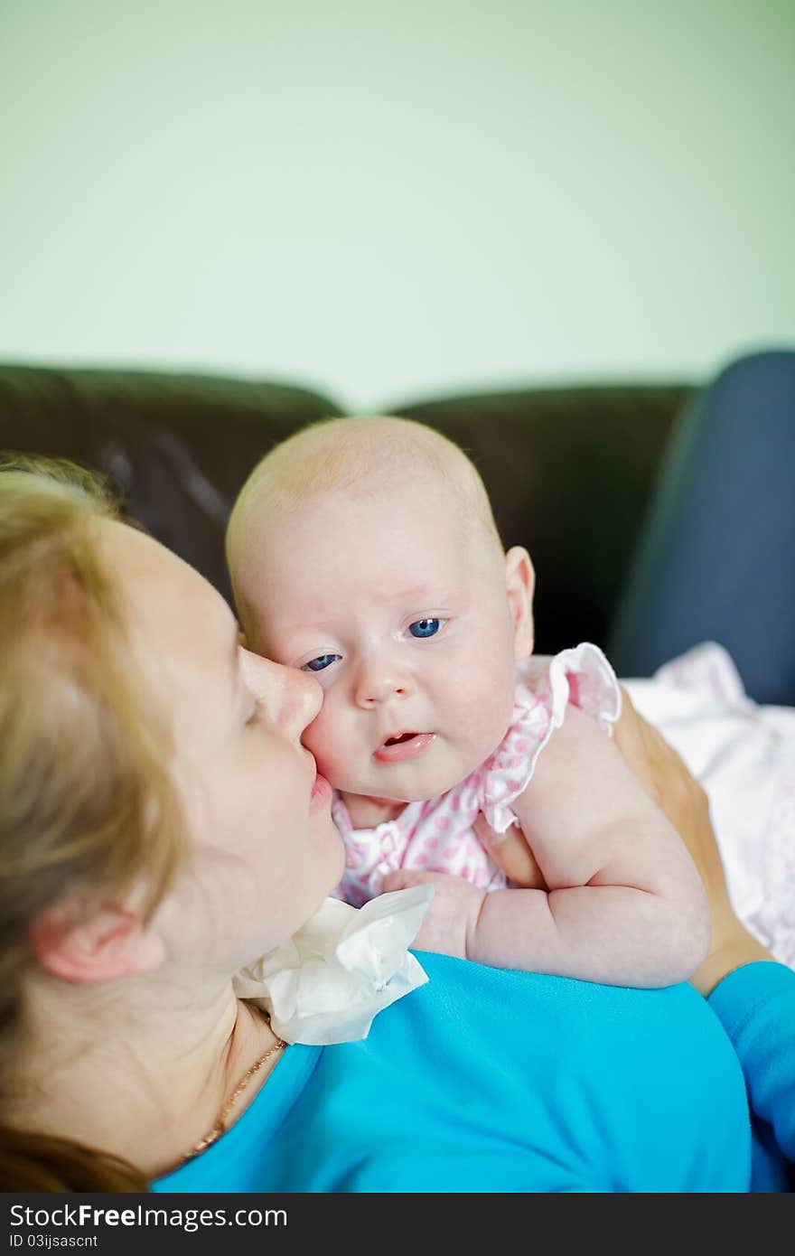 Young woman lying on her back on a couch kissing her little baby. Young woman lying on her back on a couch kissing her little baby