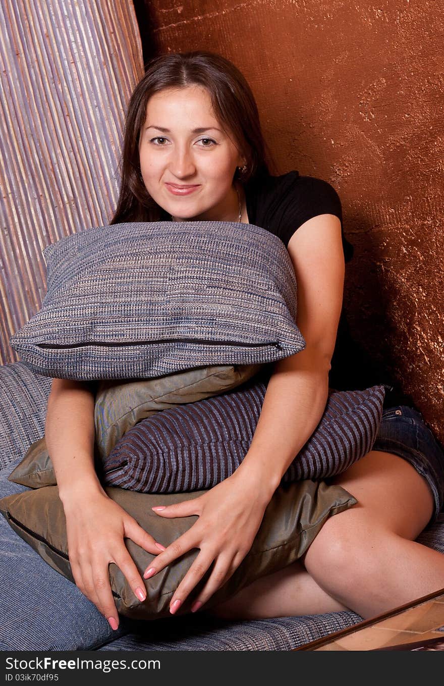 Girl sitting leaning on a lot of pillows in the interior