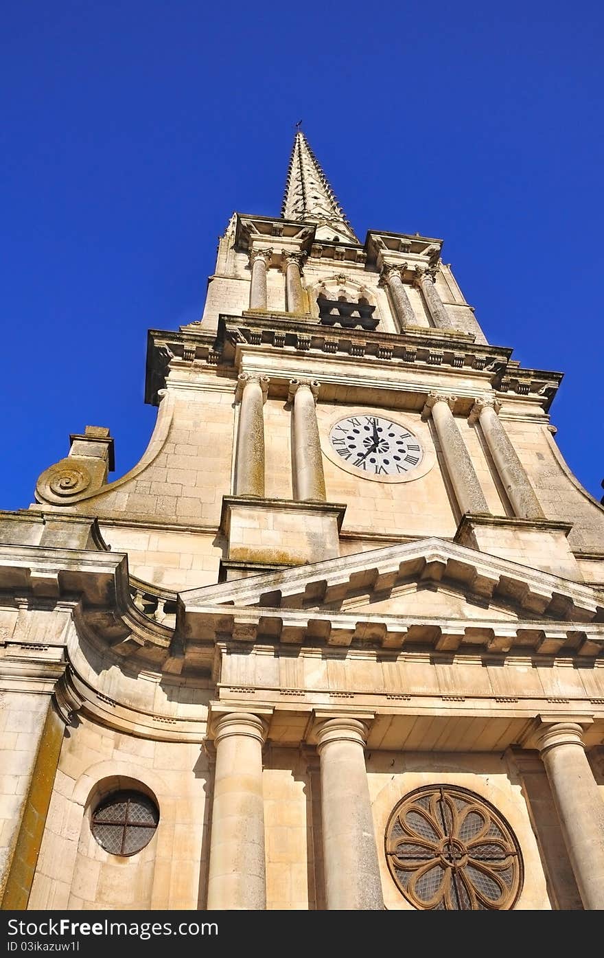 A French cathedral and its tall bell tower under a blue sky