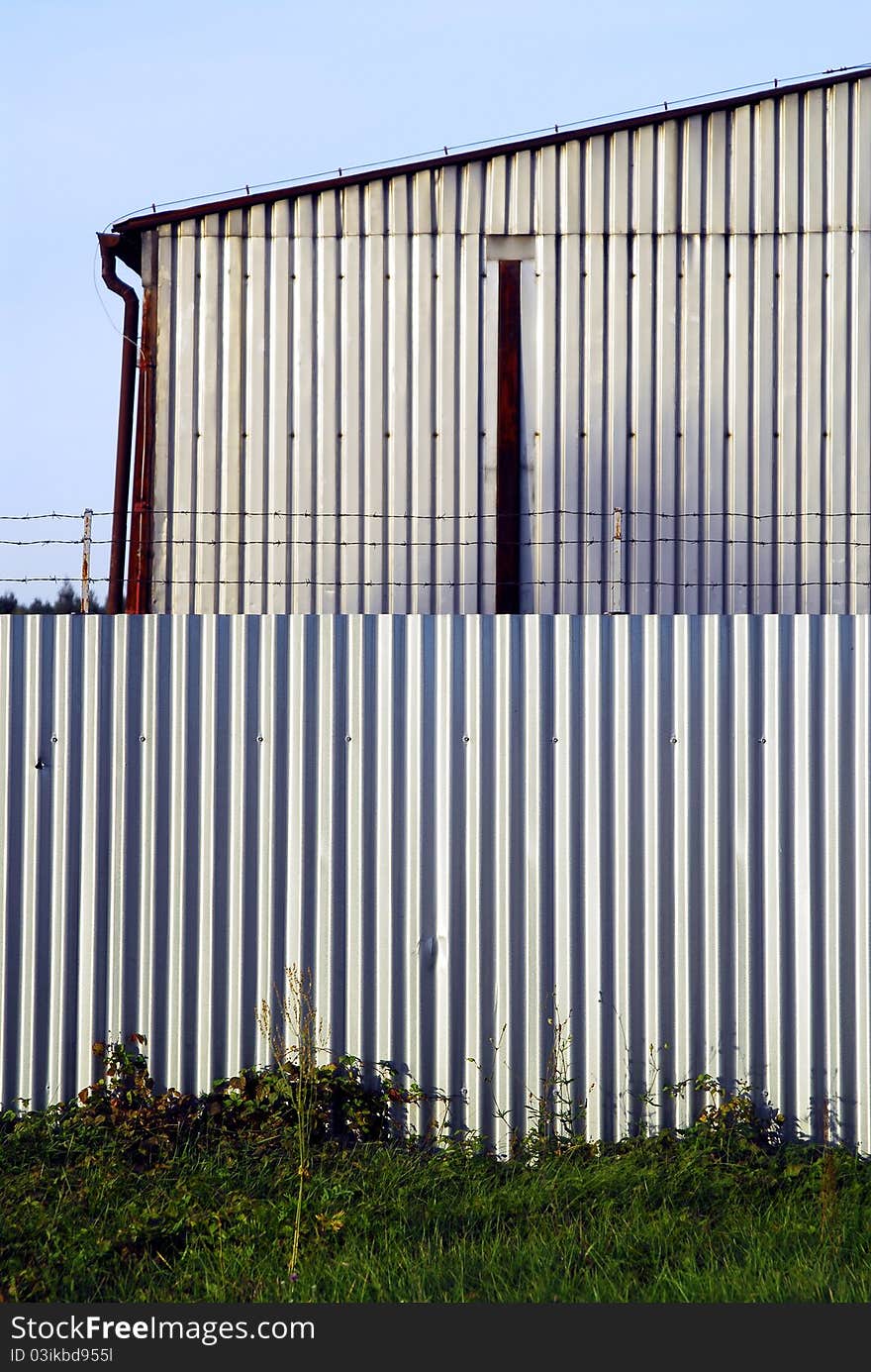 Barbed wire on the metal wall with blue sky background