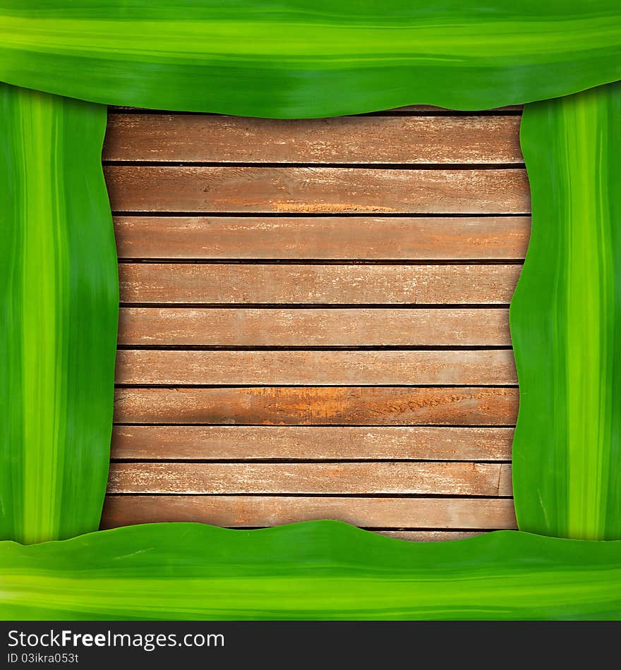 Green leaves frame on wood background