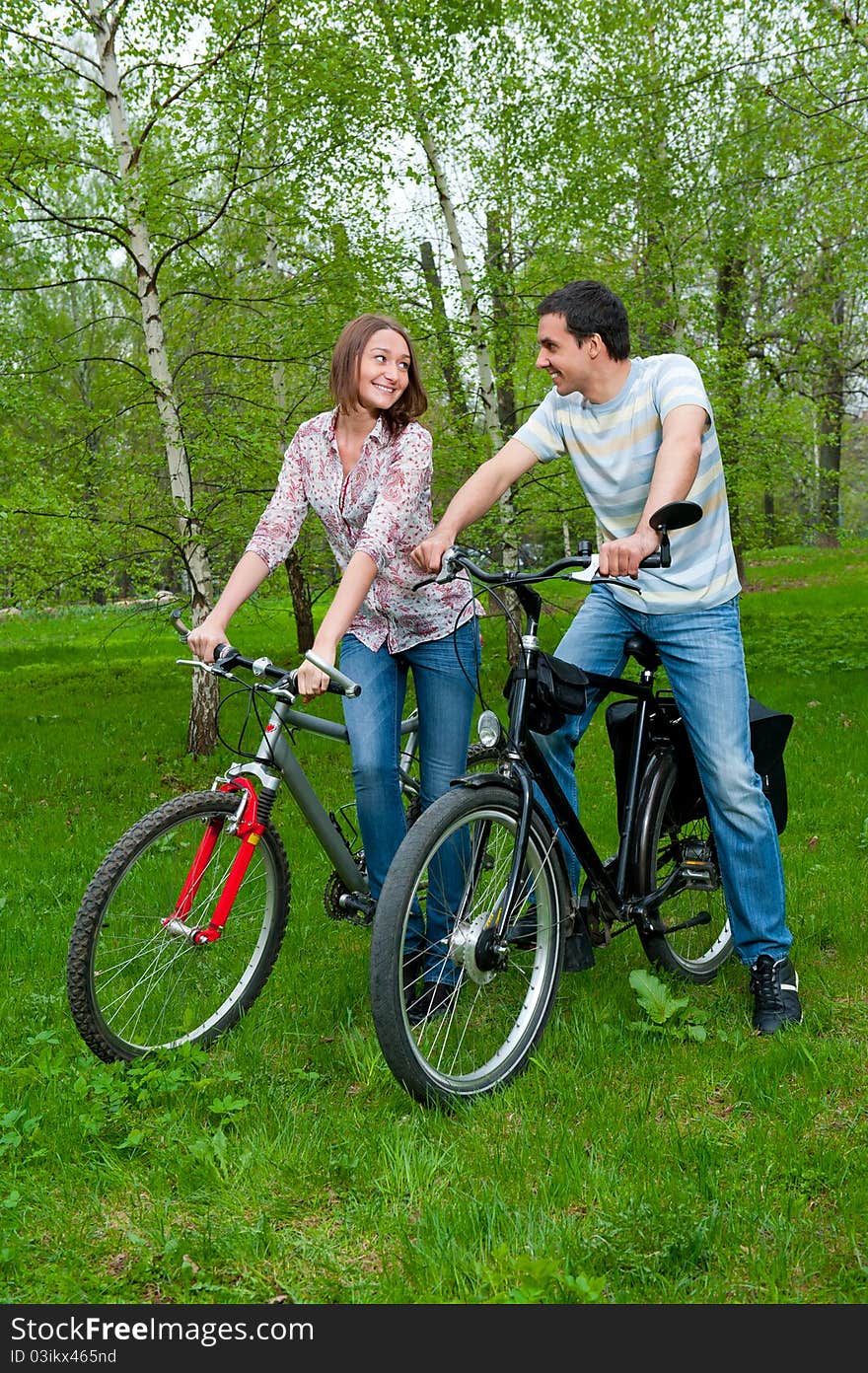 Happy young couple riding bicycles in a park