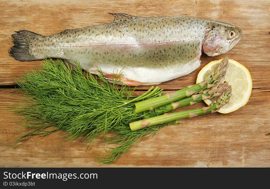 Fresh rainbow trout with dill, asparagus and lemon on old weathered wood. Fresh rainbow trout with dill, asparagus and lemon on old weathered wood