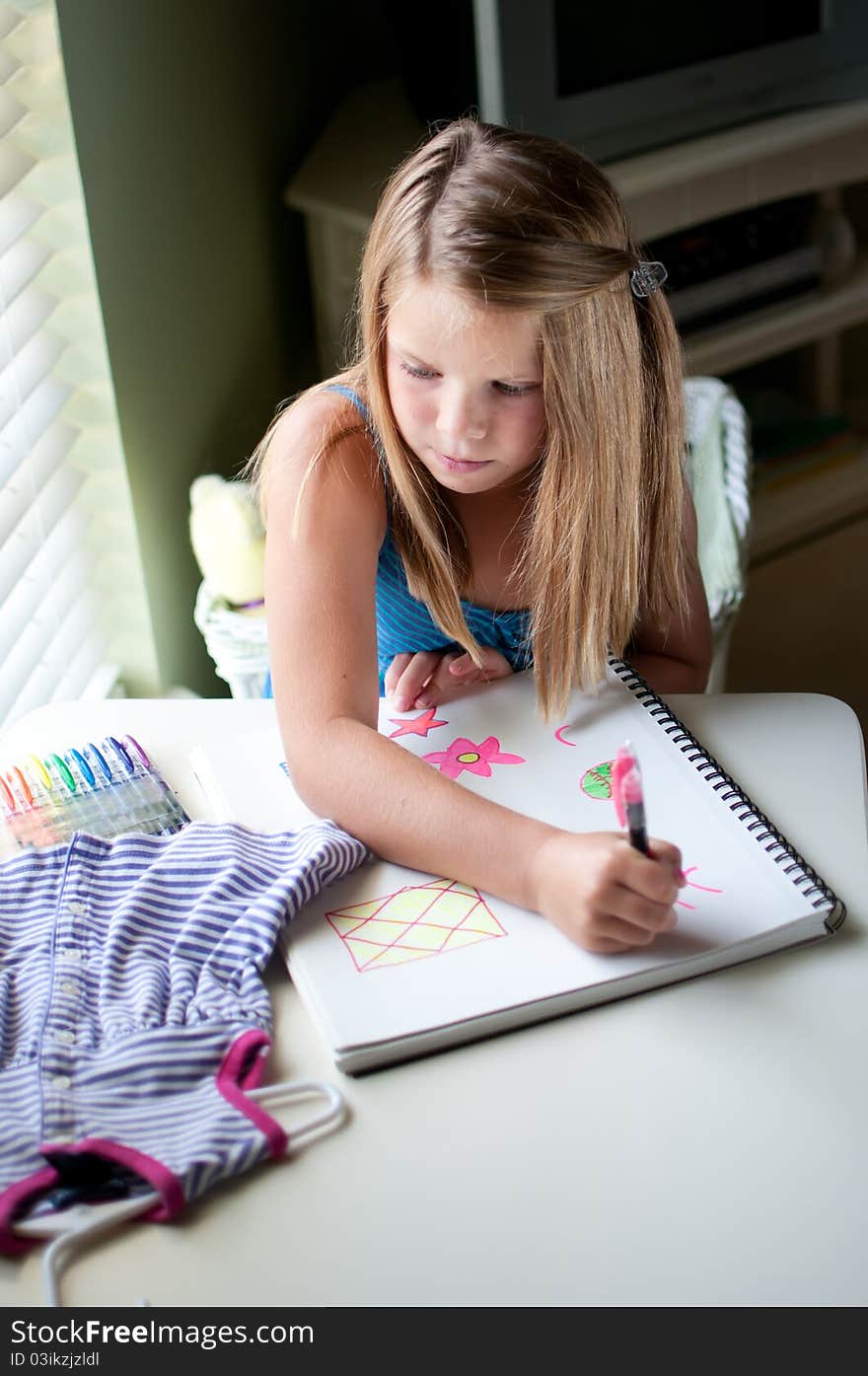 Young girl drawing clothing by window