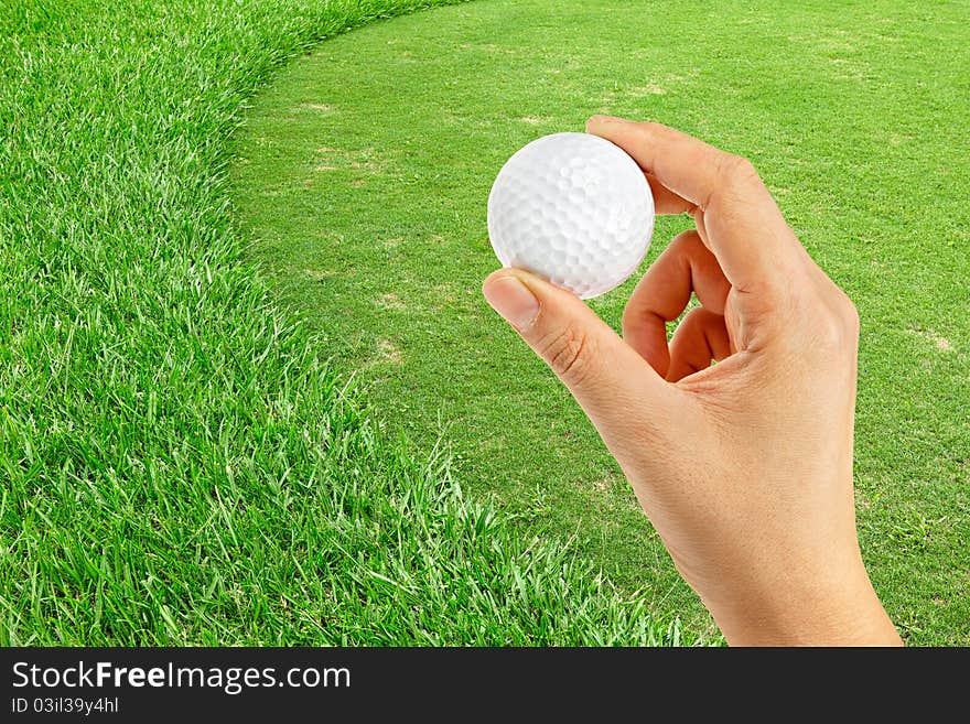 Hand holding  golf ball in green area of golf course. Hand holding  golf ball in green area of golf course