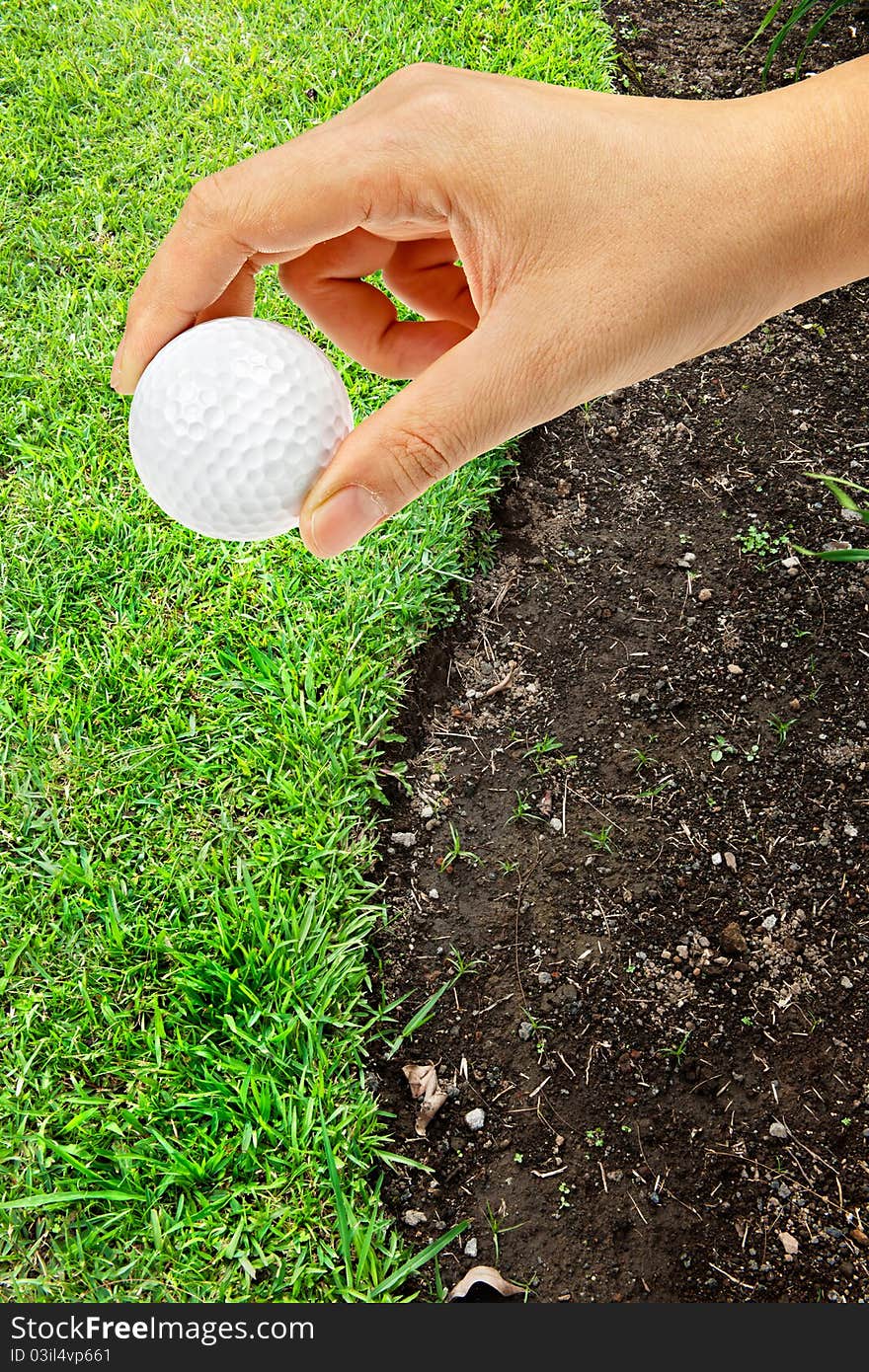 Hand holding golf ball on green grass s shape