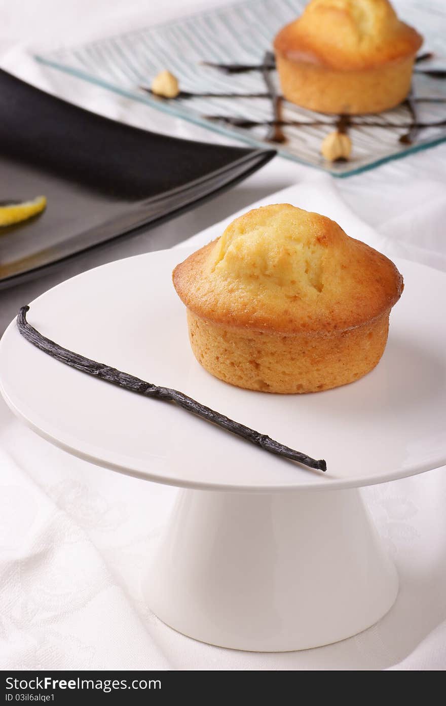 Vanilla muffin on a cake stand and assorted muffins out of focus in the background. Selective focus, shallow DOF