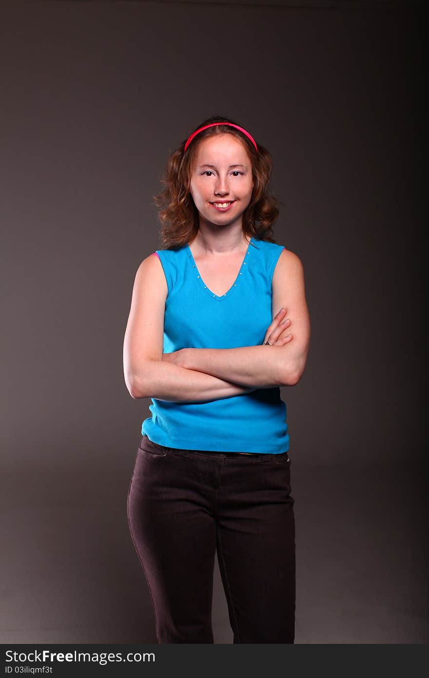 Athletic woman in sporty blue t-shirt is posing on a dark background. Athletic woman in sporty blue t-shirt is posing on a dark background.