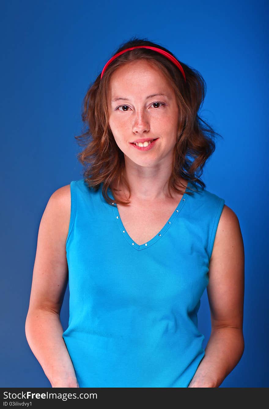 Beautiful athletic woman in sporty blue t-shirt is posing on a dark blue background. Beautiful athletic woman in sporty blue t-shirt is posing on a dark blue background.