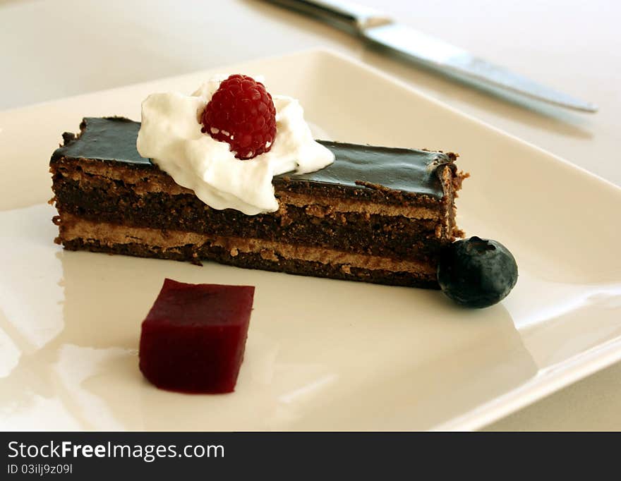 A slice of chocolate cake plated with whipped cream and berries.