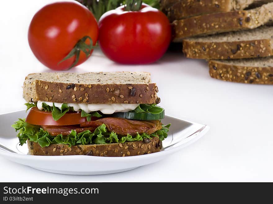 Freshly made bacon sandwich with sliced bread and tomatoes on the background. Freshly made bacon sandwich with sliced bread and tomatoes on the background