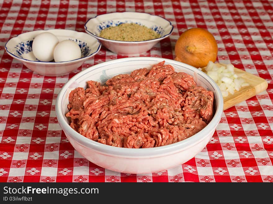 A bowl of uncooked ground beef and the ingredients in preparation of a meatloaf. A bowl of uncooked ground beef and the ingredients in preparation of a meatloaf