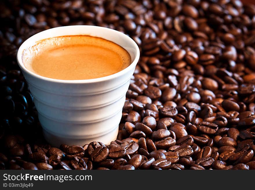 A close-up image of coffee beans with a cup of expresso