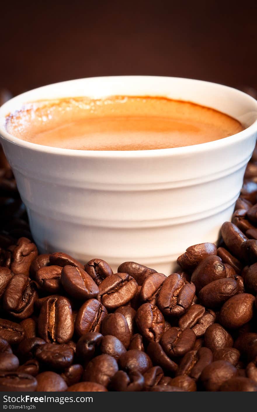 A close-up image of coffee beans with a cup of expresso