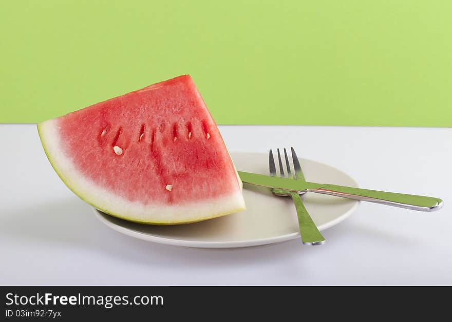 Studio-shot of a plate with fresh piece of watermelon, on a green background