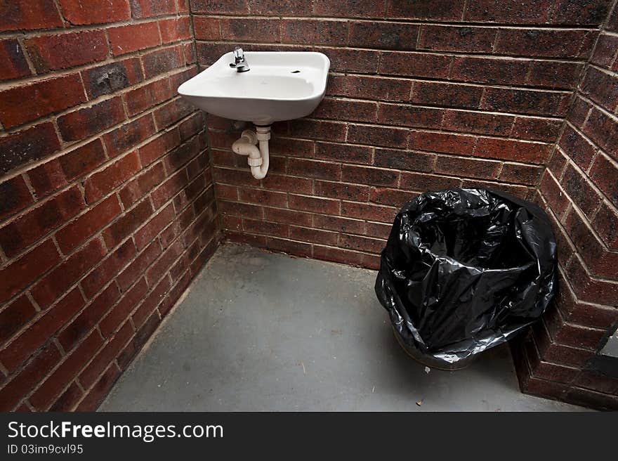 The wash sink and trash can in a public restroom. The wash sink and trash can in a public restroom.