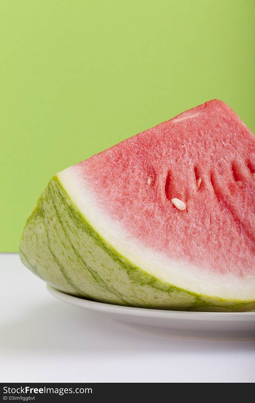 Studio-shot of a plate with fresh piece of watermelon, on a green background. Studio-shot of a plate with fresh piece of watermelon, on a green background