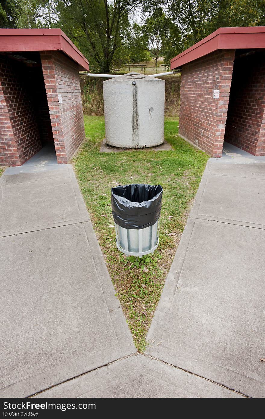 An almost mirror image of two public bathrooms with a water tank in between. An almost mirror image of two public bathrooms with a water tank in between.