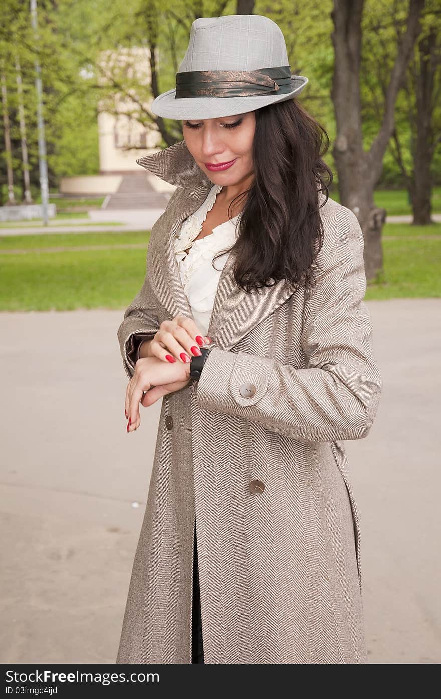 Fashion girl in a hat with a surprised look on the wrist watch. Fashion girl in a hat with a surprised look on the wrist watch