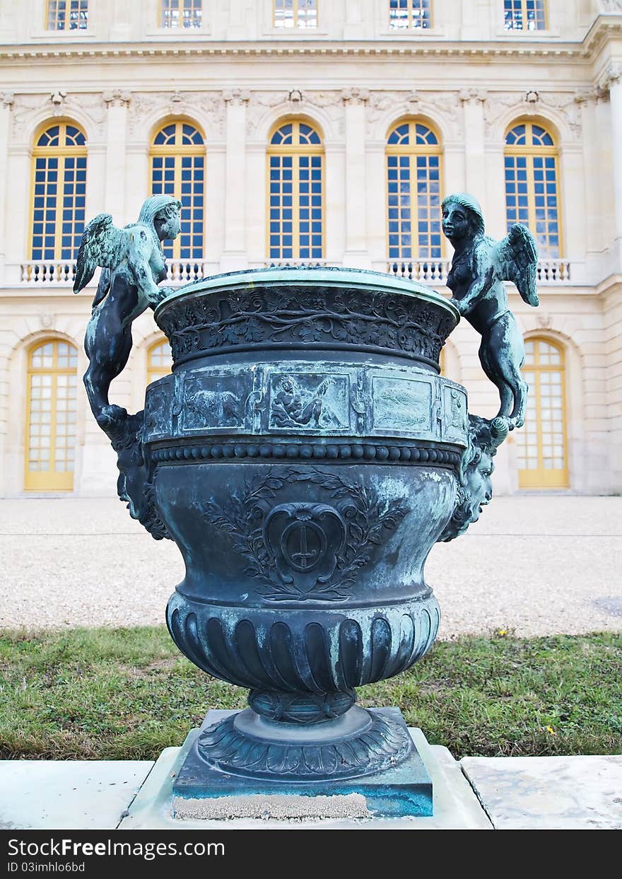 A beautiful vase with bronze angel at foreground of Castle of Versaille in France , Europe. A beautiful vase with bronze angel at foreground of Castle of Versaille in France , Europe