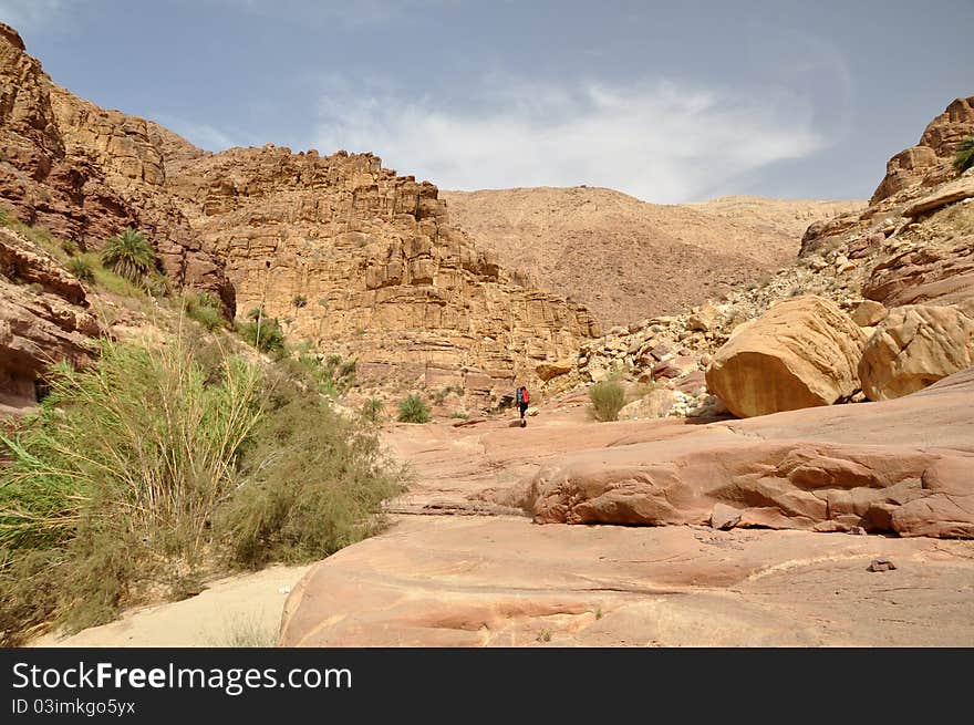 Hiker in deep canyon in desert mountains, Jordan.