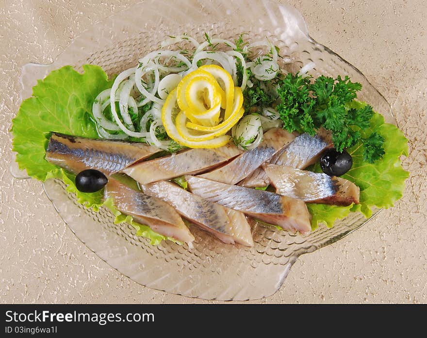 Herring fillet with onion and lemon on glass plate. Herring fillet with onion and lemon on glass plate