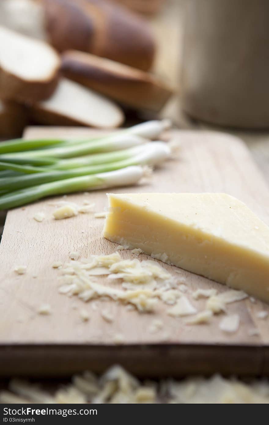 Slice of cheese on cheese board with spring onions in background