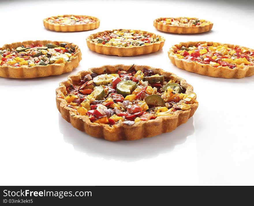 Cheese and tomato quiche arranged in rows on isolated white background