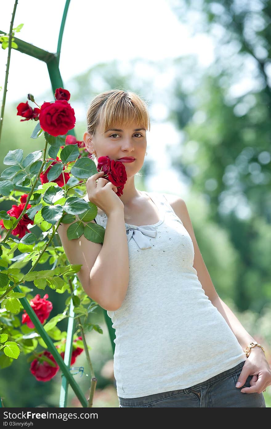 Young pretty woman holding and smelling red rose.