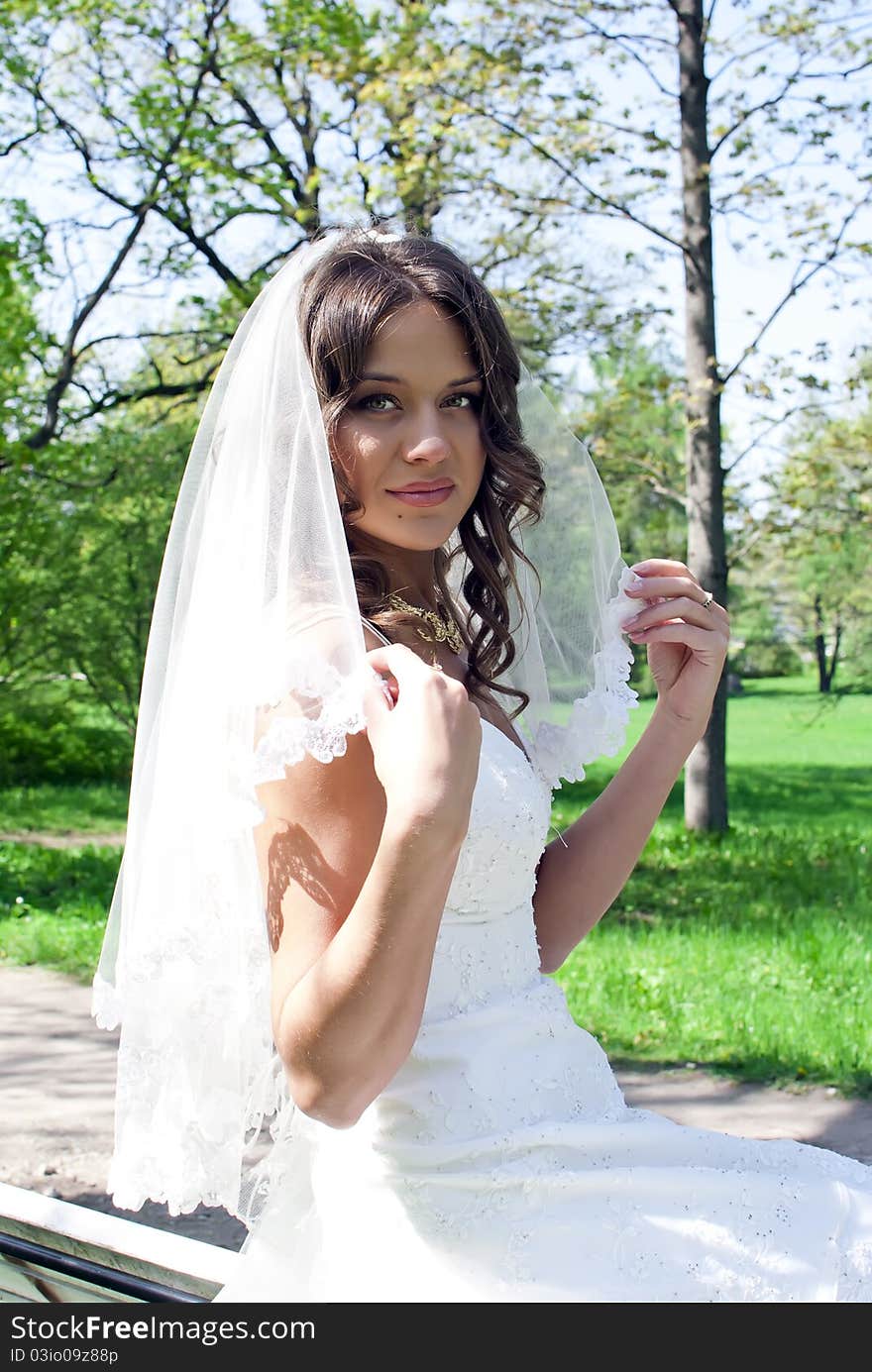 Beautiful young bride sitting on a bench