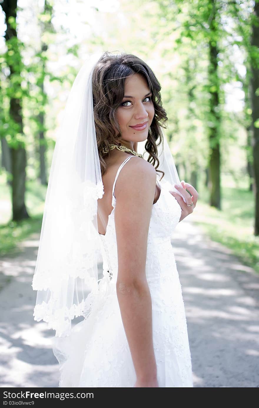 Young bride standing in an alley in the park